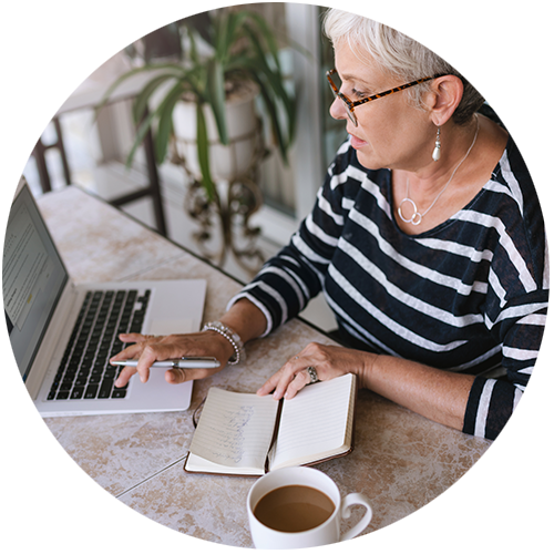 woman looking at computer while writing